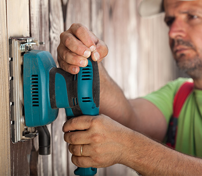 man sanding fence